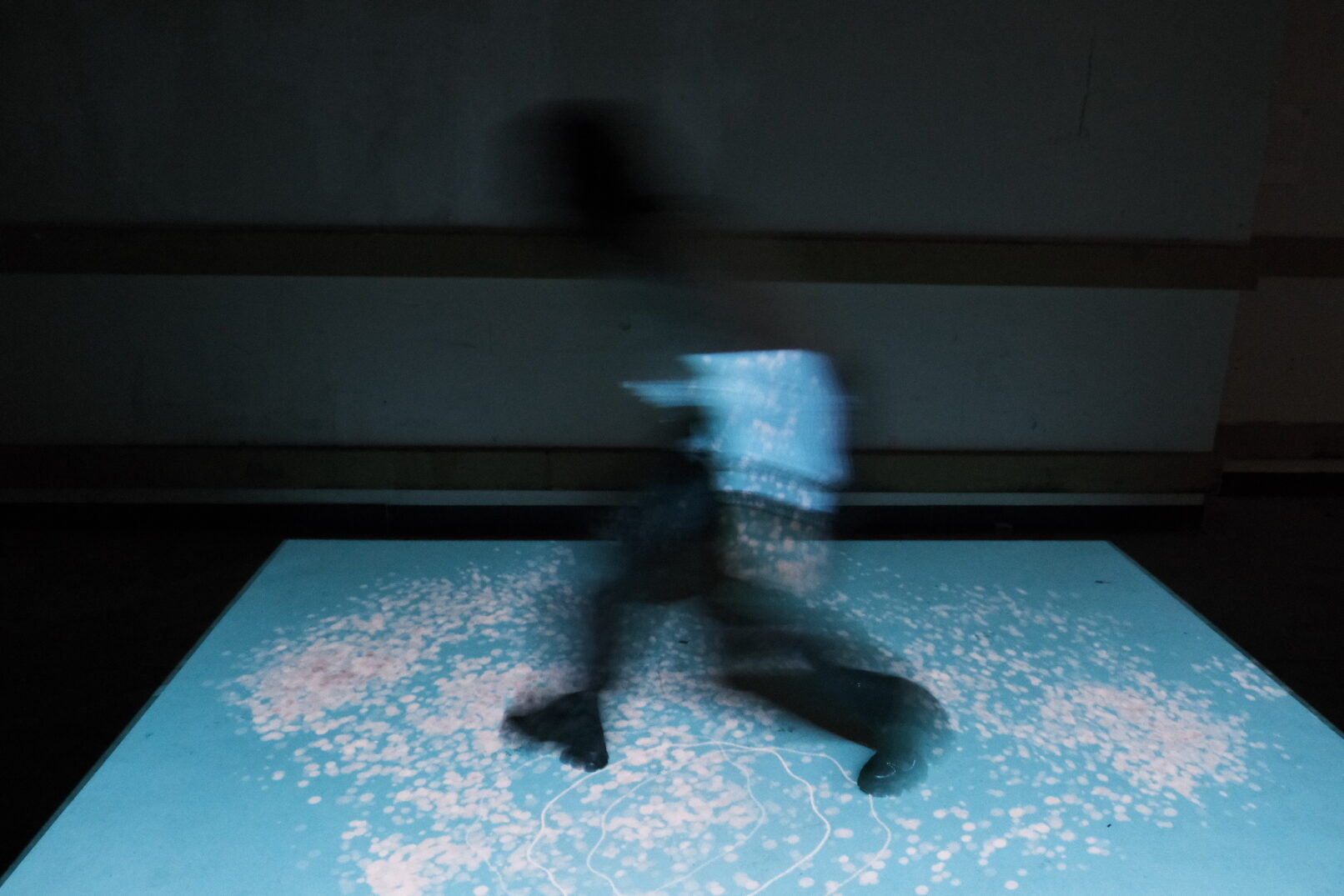 person interacts with the work of Ieva Vaiti. A sound installation with floor projection.
