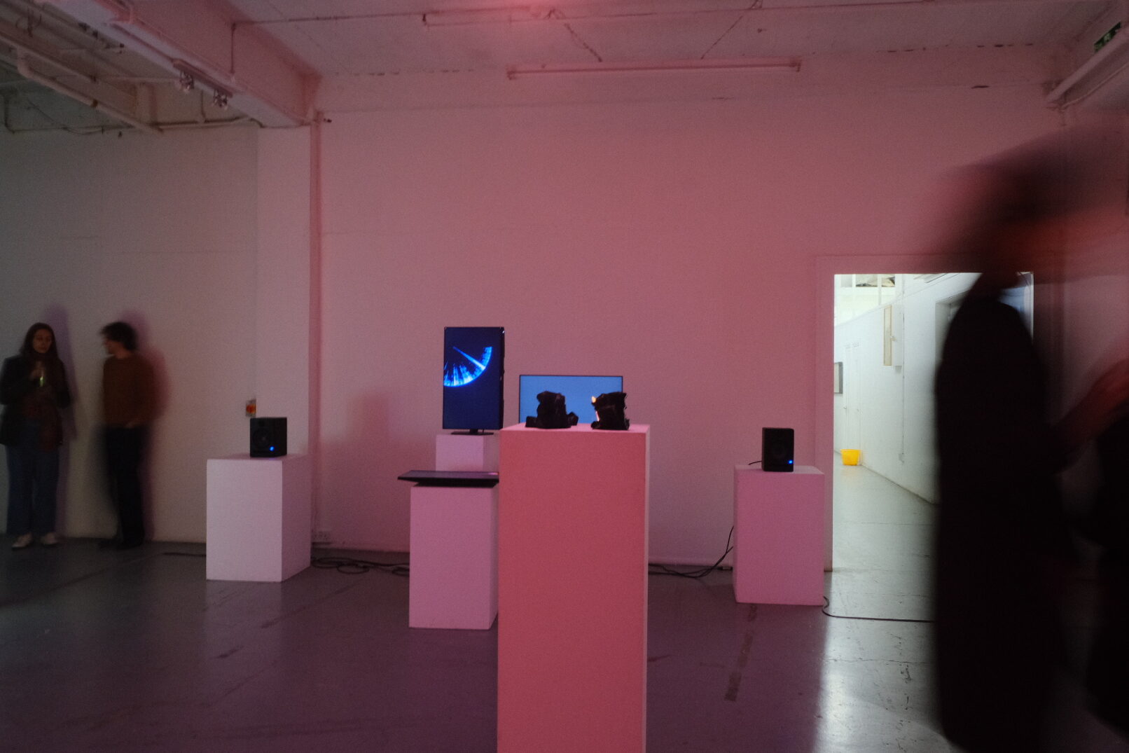 The exhibition view. In front 3D sculptures. In the background 3 screens having a generated artwork